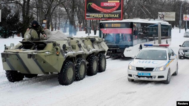 A Ukrainian armored personnel carrier tows a trolleybus behind it on a road covered with snow in Kyiv. (file photo)