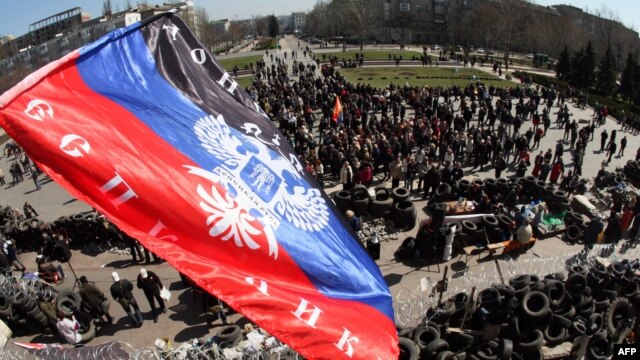The flag of the so-called 'Donetsk People's Republic' flies above a barricade and a crowd gathered in front of the Donetsk regional administration building, which is being held by pro-Russian militants. 