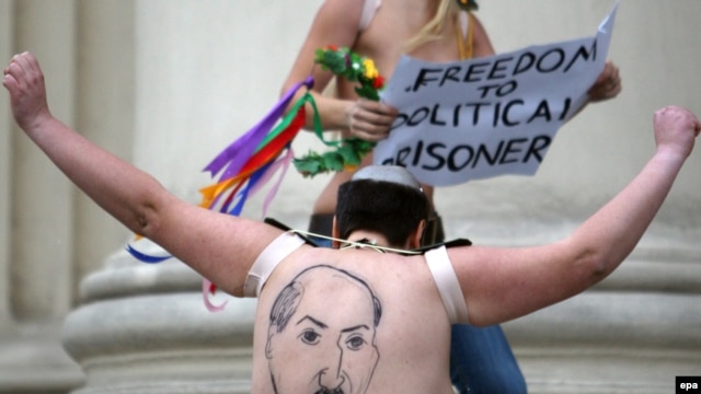 A half-naked Femen activist shows her back, where Belarusian President Alyaksandr Lukashenka is depicted, in front of the KGB headquarters in Minsk on December 19.