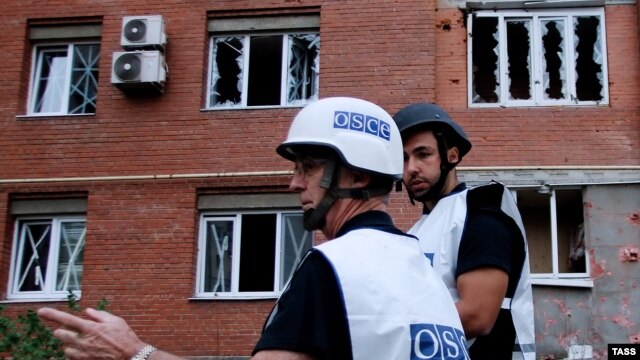 OSCE observers inspect a site near residential buildings damaged by recent shelling in Donetsk on September 9.