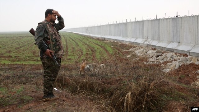 A Kurdish YPG fighter stands near a wall that activists say was put up by Turkish authorities on the Syria-Turkey border earlier this month.