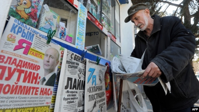 A man looks through a newspaper at a kiosk with Russian newspapers displayed outside in the Crimean port of Sevastopol on March 27.