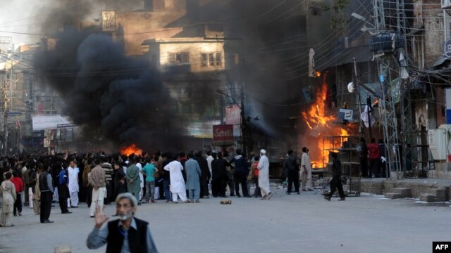 Shi'ite Muslims gather near burning shops at a market following clashes during an Ashura procession in Rawalpindi on November 15.
