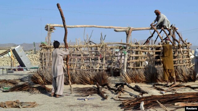 Survivors of the September 24 earthquake use poles to build a makeshift shelter near the rubble of a mud house after it collapsed in the Awaran district of Balochistan Province.