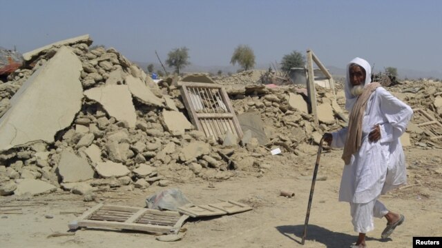 A survivor of the earthquake in Balochistan walks near the rubble of a mud house that collapsed during the temblor.