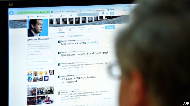 A man looks at the computer screen in Moscow with a Twitter page showing Russian Prime Minister Dmitry Medvedev.