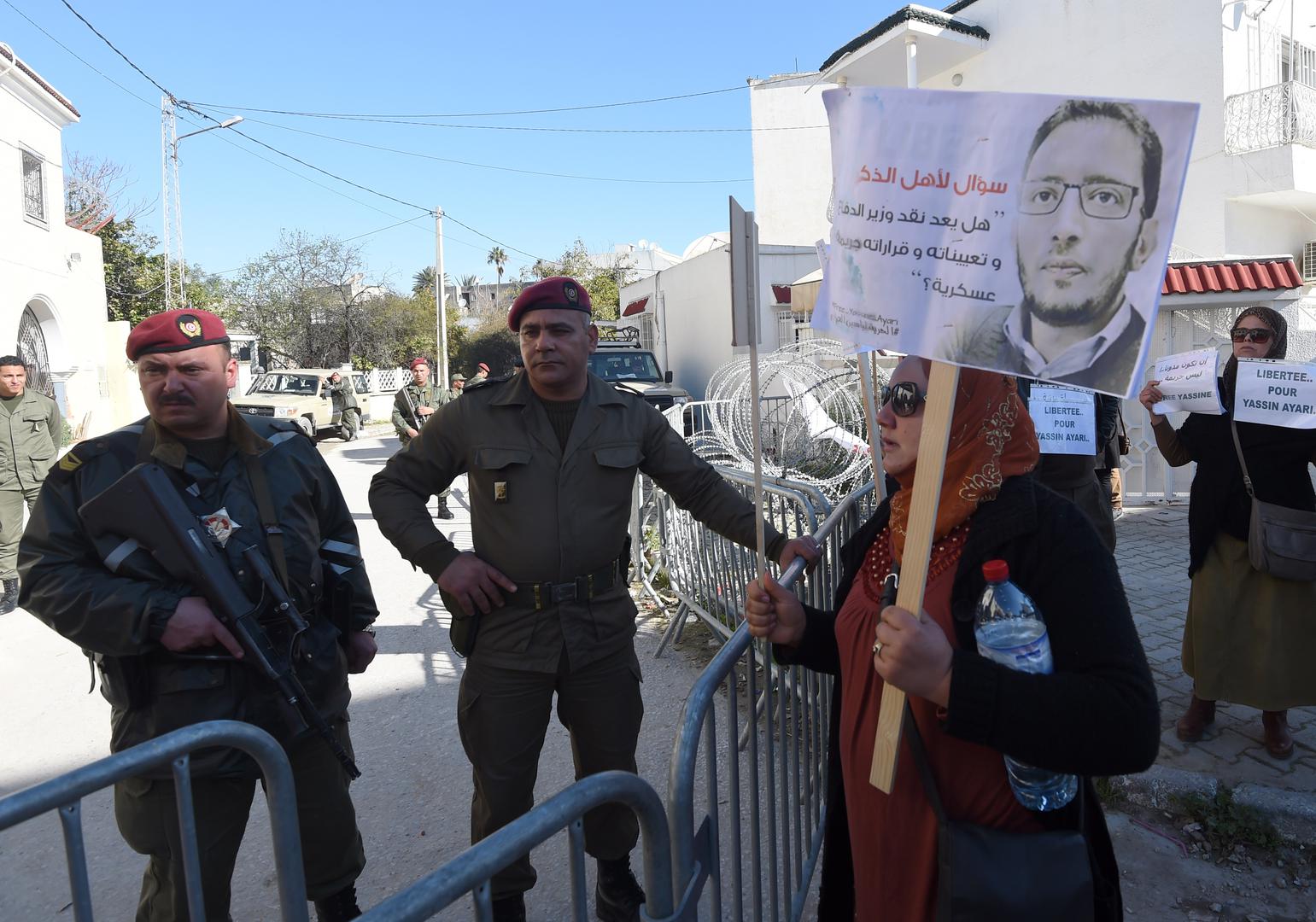 Tunisian protesters stand outside a military court in Tunis as they demonstrate in support of blogger Yassine Ayari during his appeal hearing on March 3, 2015.