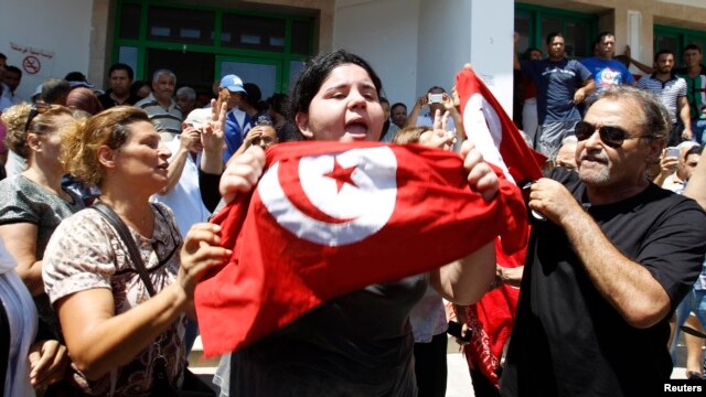 Assassinated Tunisian opposition politician Muhammad Brahmi's daughter Balkis (center) holds a Tunisian flag as she mourns his death in Tunis on July 25.