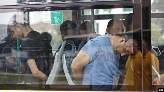 Turkish plainclothes policemen accompany soldiers, who have been detained following a failed coup attempt on July 15 , on a bus as they arrive at an Istanbul court on July 20.
