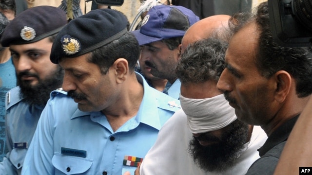 Pakistani policemen escort Imam Khalid Chishti (blindfolded) upon his arrival at a court in Islamabad on September 2.