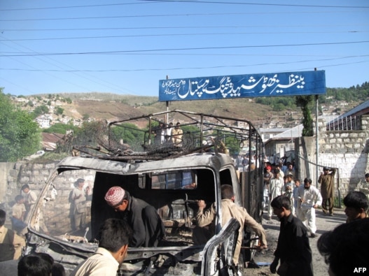 Pakistani gather around the wreckage of a police truck torched by demonstrators in Abbottabad on April 12.