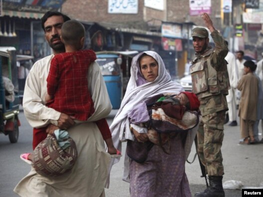 A family walks past a soldier on a street in Mingora, in Swat, on May 20.