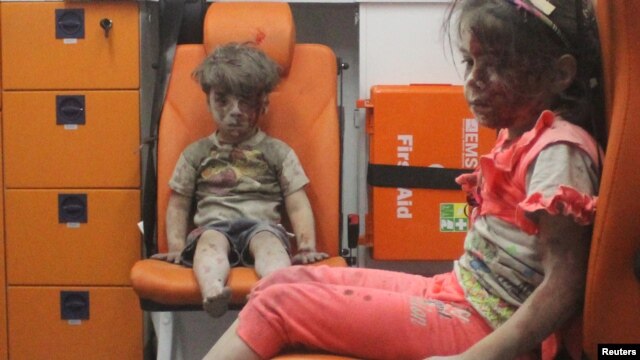 Five-year-old Omran Daqneesh, with bloodied face, sits with his sister inside an ambulance following an air strike in Aleppo.
