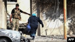 An Iraqi woman runs toward a Rapid Response forces member in Mosul's western Al-Shifa district as they battle against Islamic State fighters on June 14.