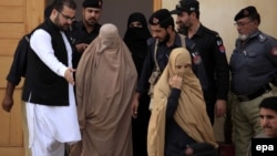 Pakistani security officials escort Afghan refugee Sharbat Gula (center, in burqa) after a court hearing in Peshawar on November 4.