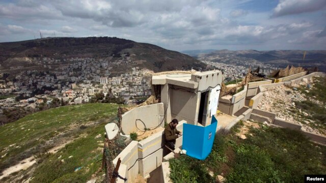 An Israeli soldier casts his ballot for the parliamentary elections behind a mobile voting booth at an army base on Mount Gerizim, near the West Bank City of Nablus, on March 17.