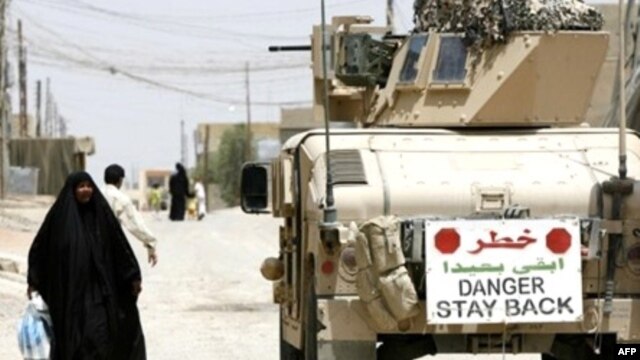 An Iraqi woman walks past a U.S. Marine vehicle on the streets in the restive city of Fallujah in 2007.