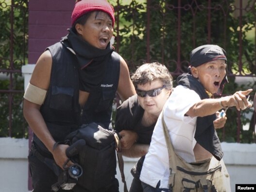 Red Shirt protesters assist an injured foreign journalist after he was shot while covering clashes with army soldiers in Bangkok on May 14.