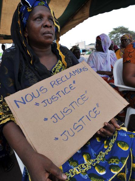 Victims of the 2010-11 post-election crisis hold placards reading 'We claim justice, justice justice' at a gathering in the Kouassai district of Abidjan on February 28, 2013, during the International Criminal Court's confirmation of charges hearing against former Ivory Coast president Laurent Gbagbo.