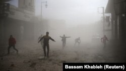 Civilians are seen running after an air raid in the besieged town of Douma in eastern Ghouta in Damascus on February 6.