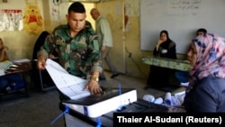 An Iraqi security member casts his vote at a polling station two days before polls open to the public in parliamentary elections in Baghdad on May 10.