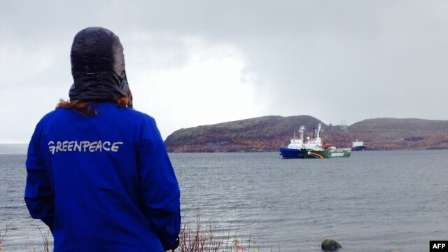 A Greenpeace activist looks at the 'Arctic Sunrise' protest ship moored next to a Russian Coast Guard vessel near Murmansk.