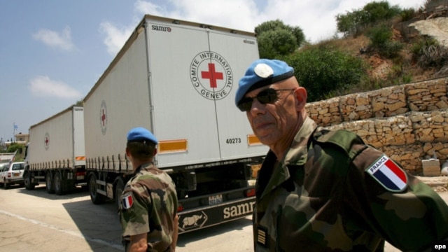 French UN peacekeeping soldiers walk behind Red Cross trucks at the Lebanese-Israeli border in 2008.