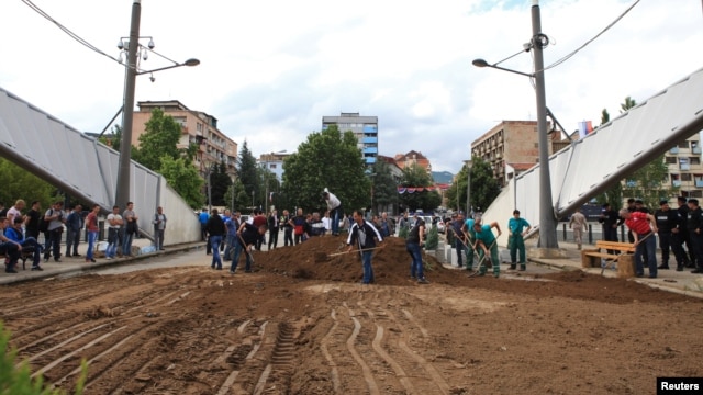 Local ethnic Serbs shovel soil to form a barricade on the main bridge in the ethnically divided Kosovo town of Mitrovica. Earlier this week a barricade on the bridge had been removed in what seemed to be the latest hint of a tentative thaw with their Albanian neighbors. But the bridge was then blocked again a a day later with concrete pots and earth.