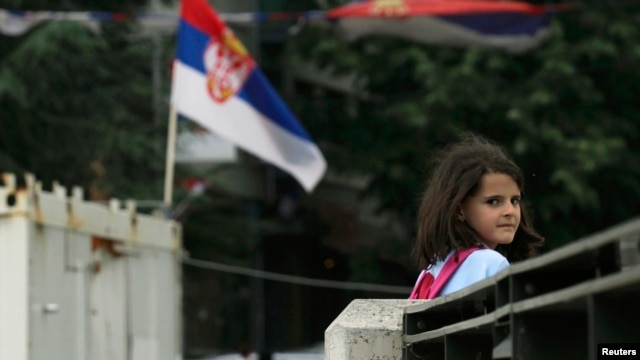 Eight-year-old Rinesa Koshi heads home past a Serbian flag as she crosses a bridge that separates the ethnically divided sections of Mitrovica, in Kosovo.