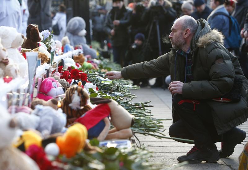 A man places flowers at a makeshift memorial for the victims of the shopping mall fire in Kemerovo, at Manezhnaya square in central Moscow, Russia March 27, 2018.