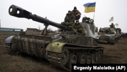 Ukrainian servicemen ride atop armored vehicles on the outskirts of Donetsk.