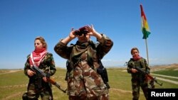 An Iraqi Kurdish female fighter looks through binoculars during a deployment near the front line of the fight against Islamic State militants in Nawaran, near Mosul, in April.