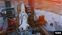 A space shuttle orbiter using an Energia rocket as a launch vehicle sits on the launch pad in the 1980s.