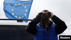 An EUMM observer watches Russian soldiers construct a fence along Georgia's de facto border with its breakaway region of South Ossetia in 2013.