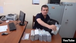 Vachagan Ghazarian empties his bag filled with cash after being arrested by the National Security Service in Yerevan on June 25.