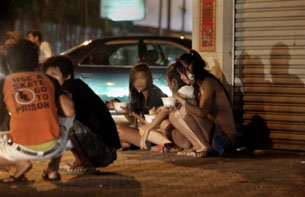 Cambodian sex workers sit on the side walk along a street in Phnom Penh on Dec. 18, 2008. AFP