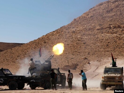 Anti-Qaddafi forces test fire a machine gun near the front line in the north of the besieged city of Bani Walid on September 11.