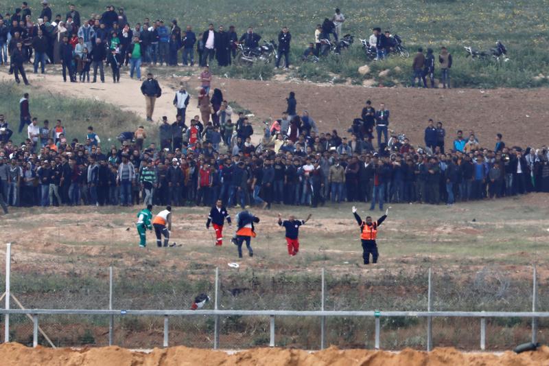 Palestinian paramedics evacuate an injured man on the Gaza side of the Israel-Gaza border, as seen from the Israeli side of the border, during March 30 Land Day demonstrations.