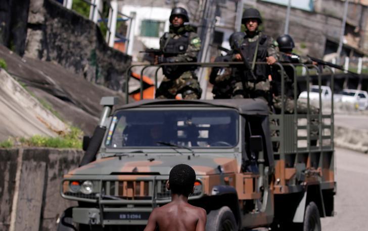 A child observes as Brazilian Armed Forces patrol, during an operation against drug gangs, in the Lins slums complex in Rio de Janeiro.