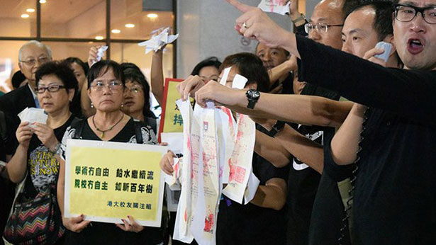 Hong Kong University (HKU) alumni look on as current students protest a university committee's decision to reject law professor and rights activist Johannes Chan for a top leadership post, Oct. 4, 2015.