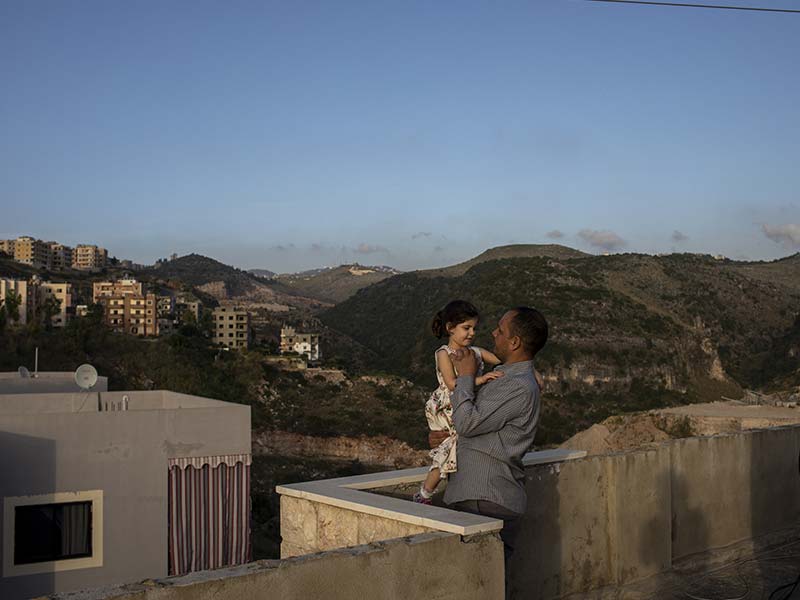 Father plays with his daughter on roof top of house