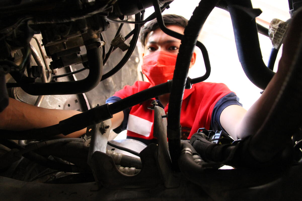 Iran. A young Afghan refugee apprentice practice his mechanic repair skills