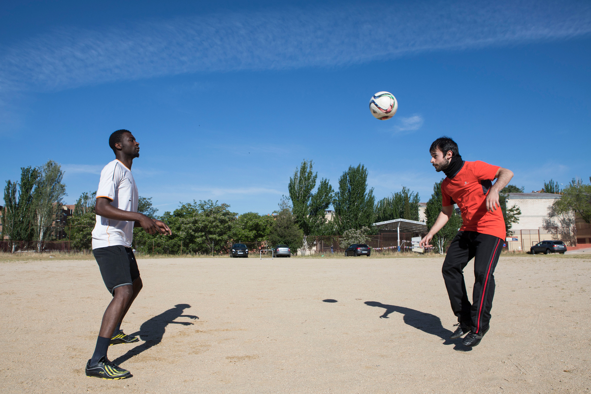 Spain. Asyum seeker Ismail plays foorball with one of his Spanish mentors, Javier while they wait for the rest of the team to arrive.